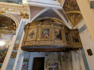 Sulla destra troviamo una raffinata cantoria in legno, decorata con riquadri di santi...